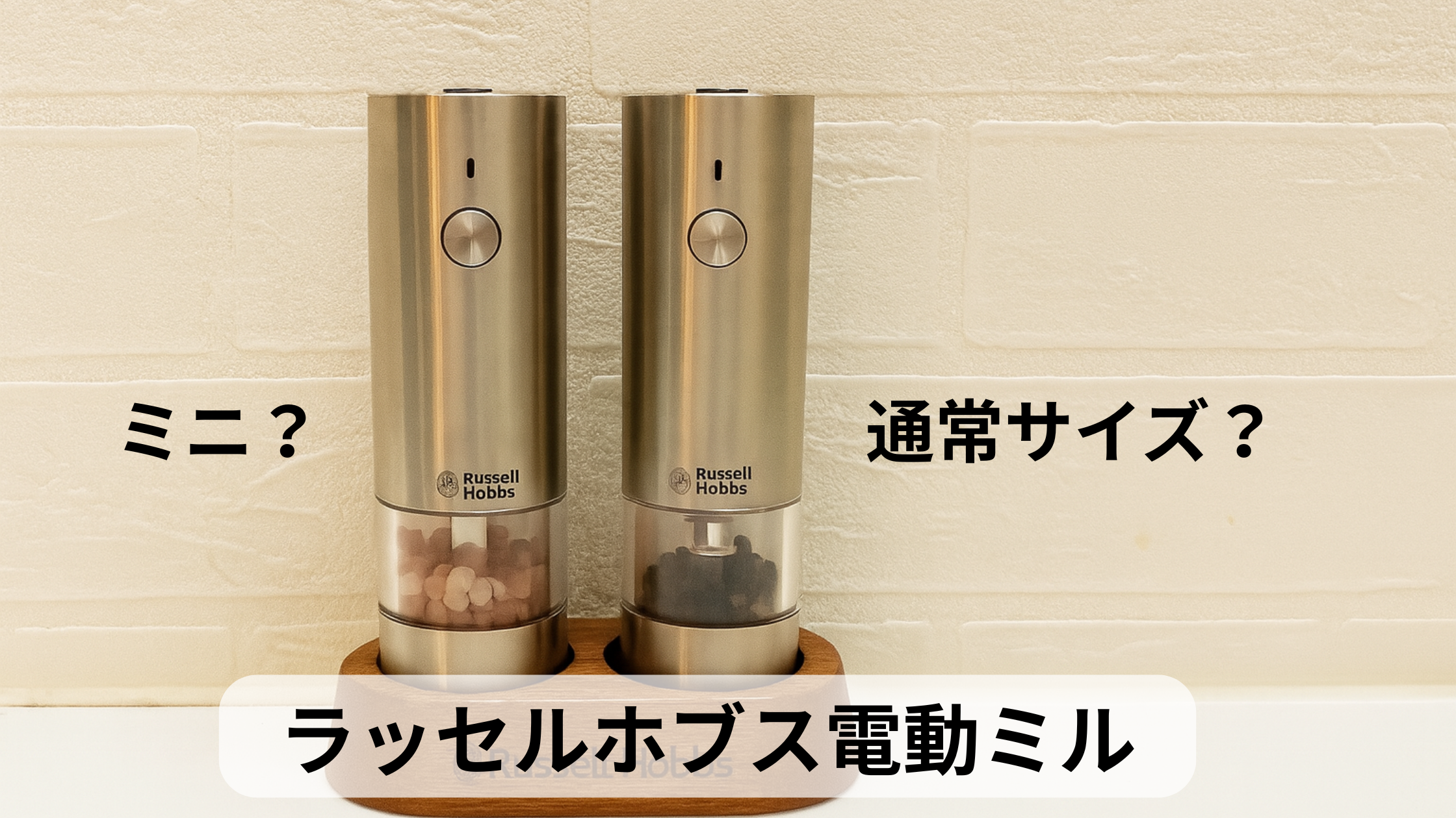 ラッセルホブスの電動ミル2本が木製スタンドに並んだ写真。左にピンクソルト、右に黒胡椒が入り、上部には“ラッセルホブス電動ミル ミニ？通常サイズ？”という比較を促すテキストが重ねられている
